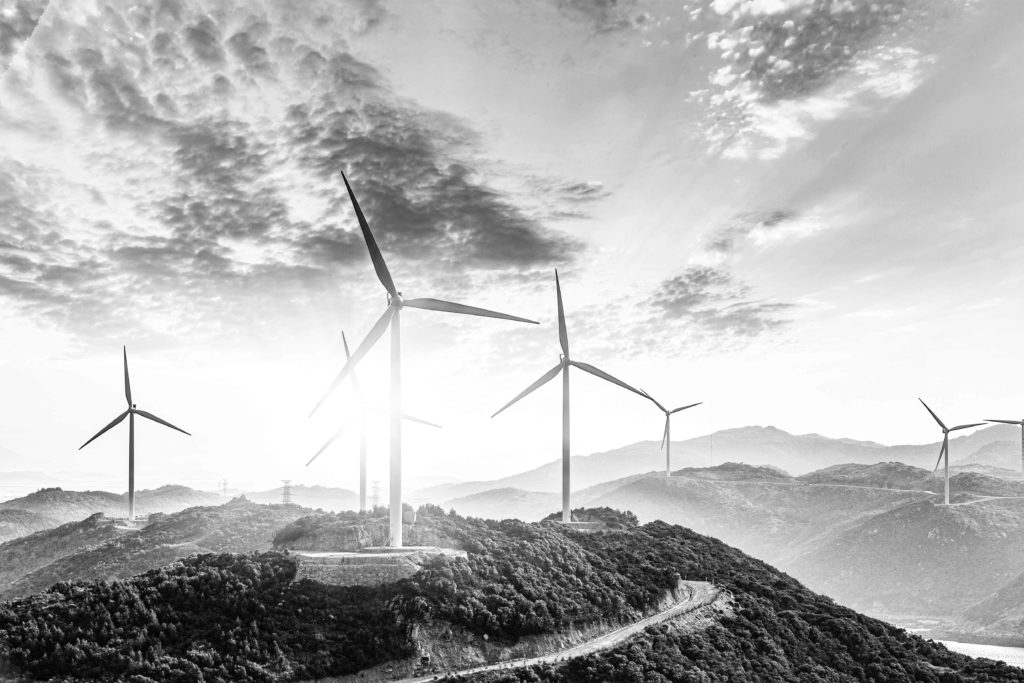 Black-and-white-picture-of-turbines-on-hill-with-sun-behind-them