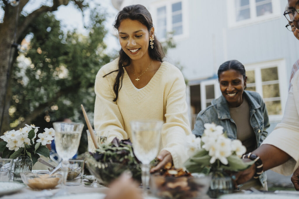 Ethnic woman and people around a table with food and drinks