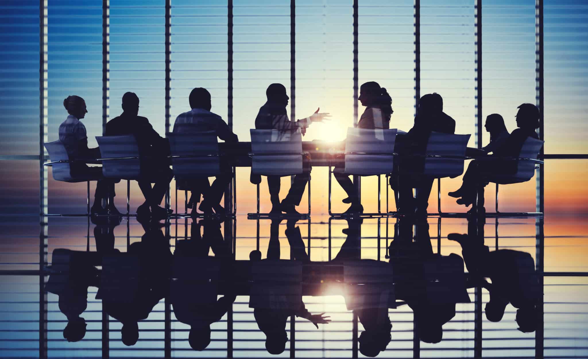 People sitting a conference table with sun setting