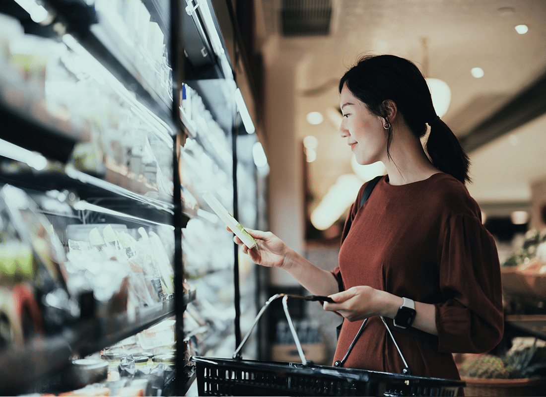 Woman-standing-holding-a-basket-looking-at-items-at-a-grocery-store